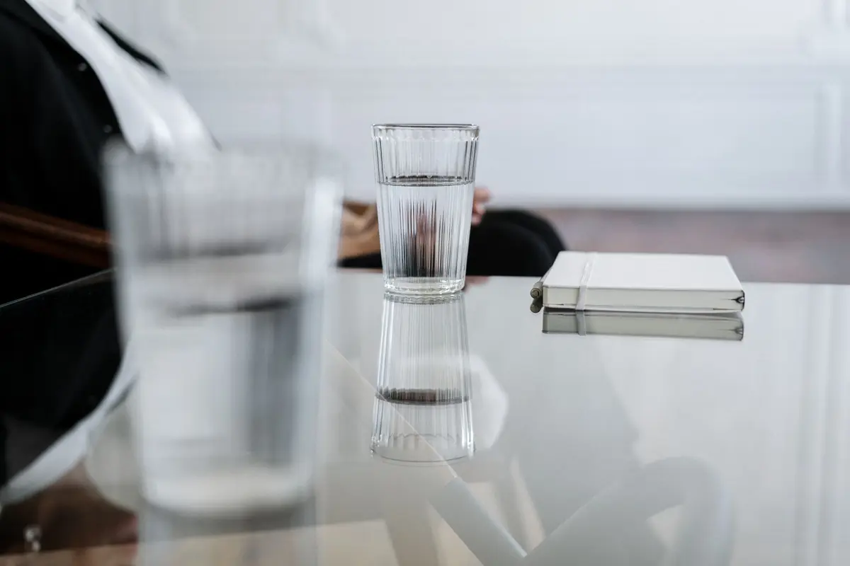 A glass of water and a notebook on a reflective table
